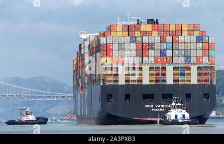 Oakland, CA - May 20, 2019: Multiple tugboats assist cargo ship MSC VANDYA to maneuver out of the Port of Oakland, the fifth busiest port in the Unite Stock Photo