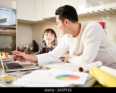 young asian man free lance designer father working at home while taking care of daughter. Stock Photo