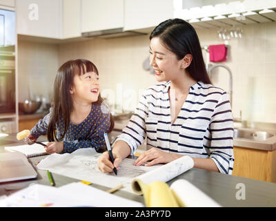 young asian design professional mother working at home while taking care of daughter. Stock Photo