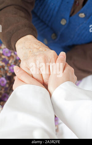 Young doctor holds the old woman's hand Stock Photo