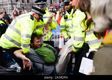 Police officers arrest a member of climate change activist movement, Extinction Rebellion (XR) refusing to move on from an encampment on Victoria Street during the third day of the group's 'International Rebellion' in London.Police officers continue to clear demonstrators and tents from sites across Westminster, with activists having been warned about moving to a designated protest area around Nelson's Column in Trafalgar Square or face arrest. Similar blockades by Extinction Rebellion in April, at sites including Oxford Circus and Waterloo Bridge, saw more than 1,000 arrested, a tactic promot Stock Photo