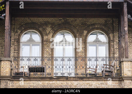 An ornate  older house with a nice bright balcony with chairs and tables Stock Photo