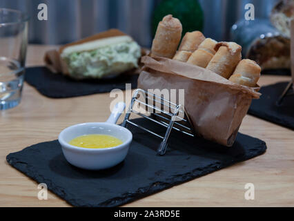 Tequeños typical Venezuelan food, cheese fingers served in paper bag on stone plate Stock Photo