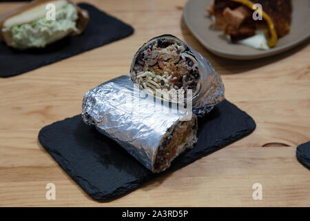 Beef burrito with rice and beans wrapped in silver paper on stone plate, typical Latin cuisine Stock Photo