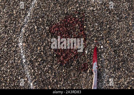 Close up of Crime scene chalk outline of victim dead body on Road with bloody knife and blood on road Stock Photo