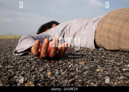 Concept of Crime scene ,Selective focus to victim hand with blood of a dead body laying on Road. Stock Photo