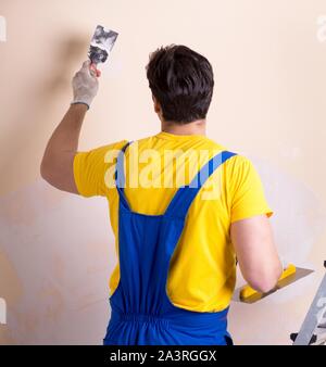 The young contractor employee applying plaster on wall Stock Photo