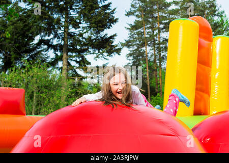 Happy little girl having lots of fun on a inflate castle while jumping. Stock Photo