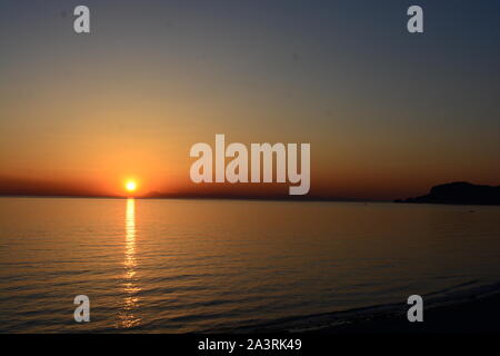 Alanya Sunset, The sun setting over the ocean with Alanya Castle silhouetted agains the horizon and a calm ocean in Spring time Stock Photo