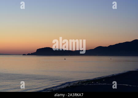 Alanya Sunset, The sun setting over the ocean with Alanya Castle silhouetted agains the horizon and a calm ocean in Spring time Stock Photo