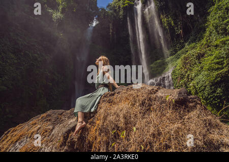 Woman in turquoise dress at the Sekumpul waterfalls in jungles on Bali island, Indonesia. Bali Travel Concept Stock Photo
