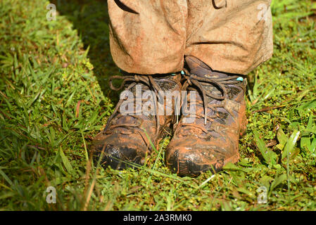 A close up of  muddy hiking boots and dirty trousers after an adventurous walk in the rainforest. Madagascar Stock Photo