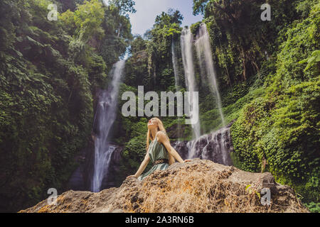 Woman in turquoise dress at the Sekumpul waterfalls in jungles on Bali island, Indonesia. Bali Travel Concept Stock Photo