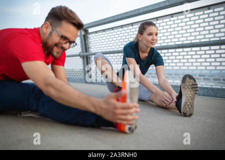 Fitness, sport, training and lifestyle concept. Fit couple friends stretching outdoors Stock Photo