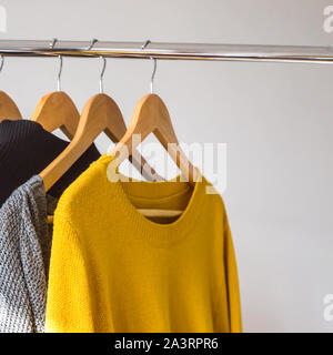 Autumn female gardera on hangers of a sweater and a coat of yellow and gray colors Stock Photo