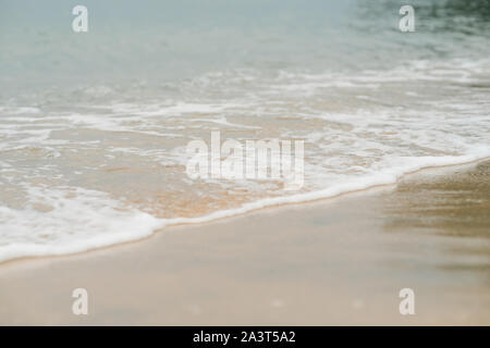 Soft waves with foam of ocean on the sandy beach background Stock Photo