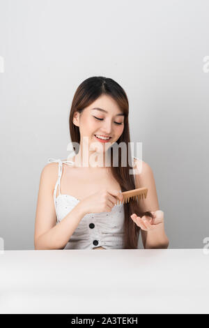 young beautiful woman combing her hair isolated on white background Stock Photo