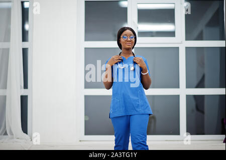 Portrait of happy female african american young doctor pediatrician in blue uniform coat and stethoscope against window in hospital. Healthcare, medic Stock Photo