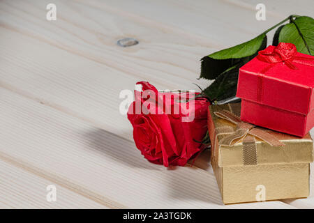 Red rose and two gift boxes on wooden background, copy space image Stock Photo