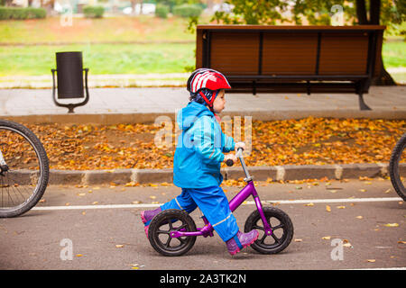 Little kid riding on balance bike, follow the parents Stock Photo