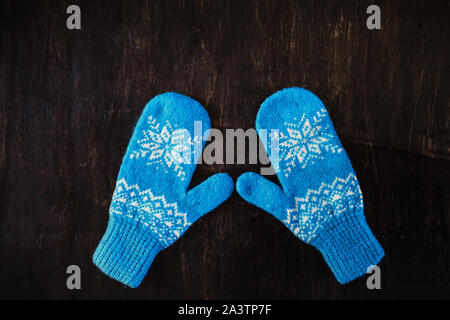 a pair of blue knitted mittens on a dark blue-green-brown wooden Stock Photo