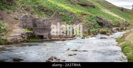 Panorama of the ruins of an old stone mill standing by the river Stock Photo