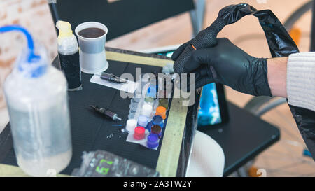 Close-up of tattoo artist work place parts and paint, machines and other equipment. Professional tattooist working tattooing in studio. Process of mak Stock Photo