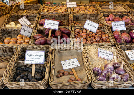 various types of red onion, garlic and potatoes in wicker baskets,at street food market. Stock Photo