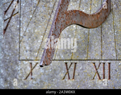 Gnomon of a wall mounted sundial with Roman numerals marking the time - UK Stock Photo