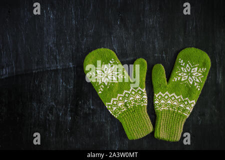 a pair of blue-green knitted mittens on a dark blue-green-brown wooden Stock Photo