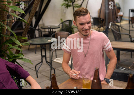 Happy man laughing and smoking cigarette while drinking beer Stock Photo