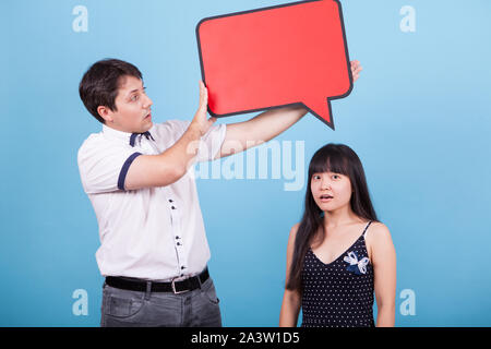 Shocked asian girlfriend while boyfriend holding empty sign over her head. Interracial couple. Stock Photo