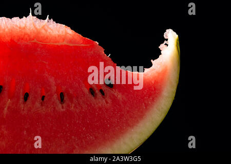 Bit slice of watermelon with seeds on black background Stock Photo