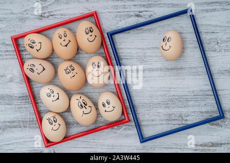 Picture red and blue frame and many funny eggs smiling on white wooden wall background, close up. Eggs family emotion face portrait. Concept funny foo Stock Photo