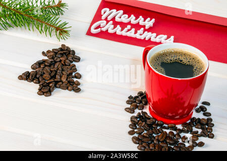 Christmas coffee card with red cup of coffee and christmas tree made of coffee beans and in background red envelope with Merry Christmas words, copy s Stock Photo