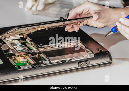 Woman engineer remove the cover of laptop using tool Stock Photo