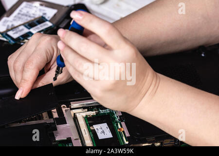 Woman engineer remove the cover of laptop using tool Stock Photo