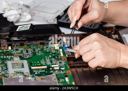 Closeup photo of woman engineer replace computer part from notebook motherboard Stock Photo