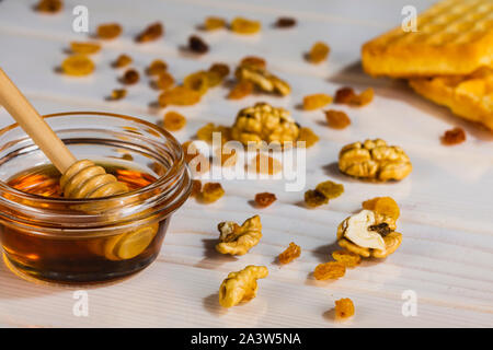 Bowl with honey and core walnuts on white wooden table Stock Photo