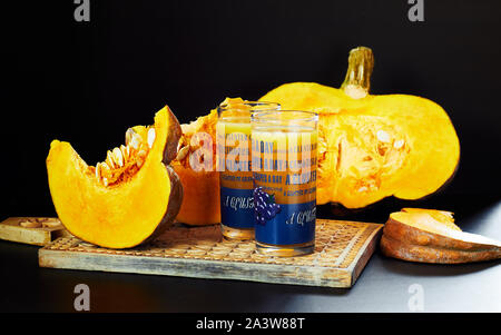 Glaces of fresh pumpkin juice, healthy homemade drink made from vegetable, cut pieces of squash layinig nearby on wooden cutting board, still life com Stock Photo