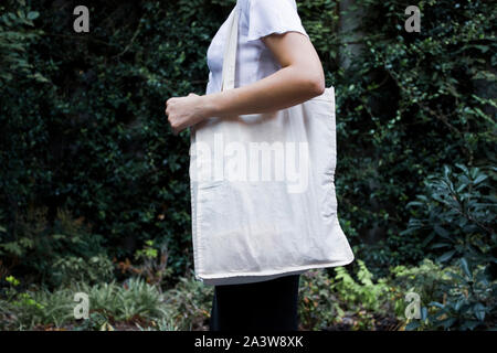 Blank white shopping canvas fabric cloth bag on female holding mockup and template isolated natural background Stock Photo