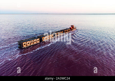 Awesome train rides on the rail in the water with white salt on the background of beautiful blue sky. aerial view, view from the top Stock Photo