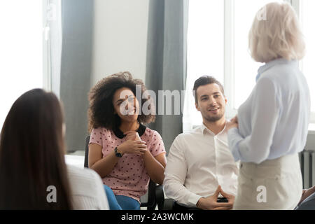 Diverse trainee sitting on office chairs listening mature business coach Stock Photo