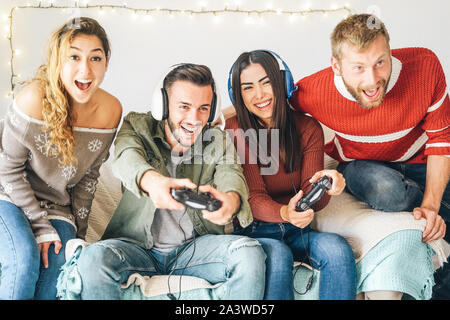 Millennial friends playing video games online with headset - Young people having fun with new trends technologies Stock Photo