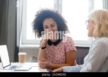 Diverse employees sitting at desk laughing take break from work Stock Photo
