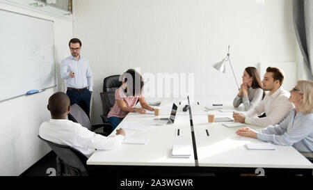 Male business coach giving presentation to diverse company staff Stock Photo