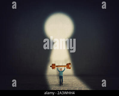 Confident businessman carries a golden key over head, found the way to success, has to open the lock. Ambition and business motivation concept. Unlock Stock Photo