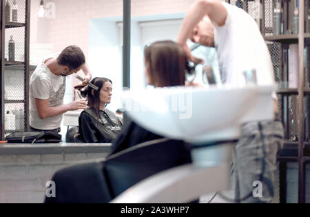 Moscow, Russia - Oct 10, 2019: Professional hairdresser working with client in salon. Male hair stylist and female customer in salon. Stock Photo