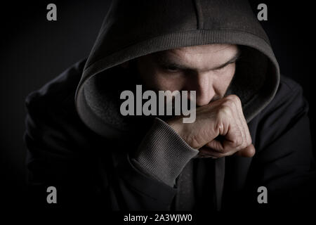 Thoughtful man with hood looking worried. Stock Photo