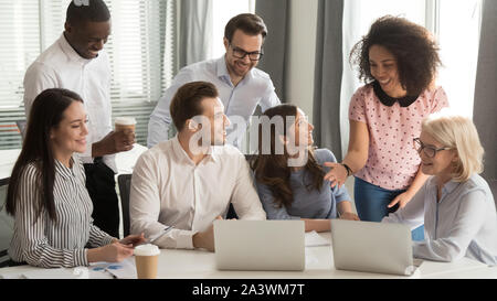 Laughing multiracial office workers sitting in boardroom having funny break Stock Photo